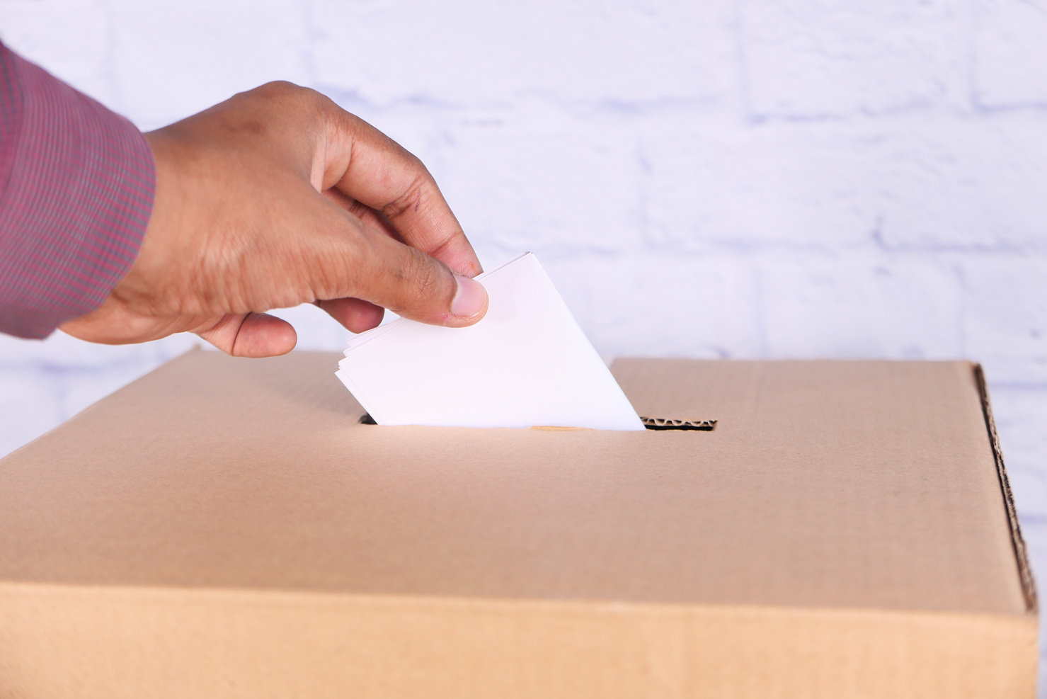 Close up of Man's Hand Putting Card in Box with Slot,